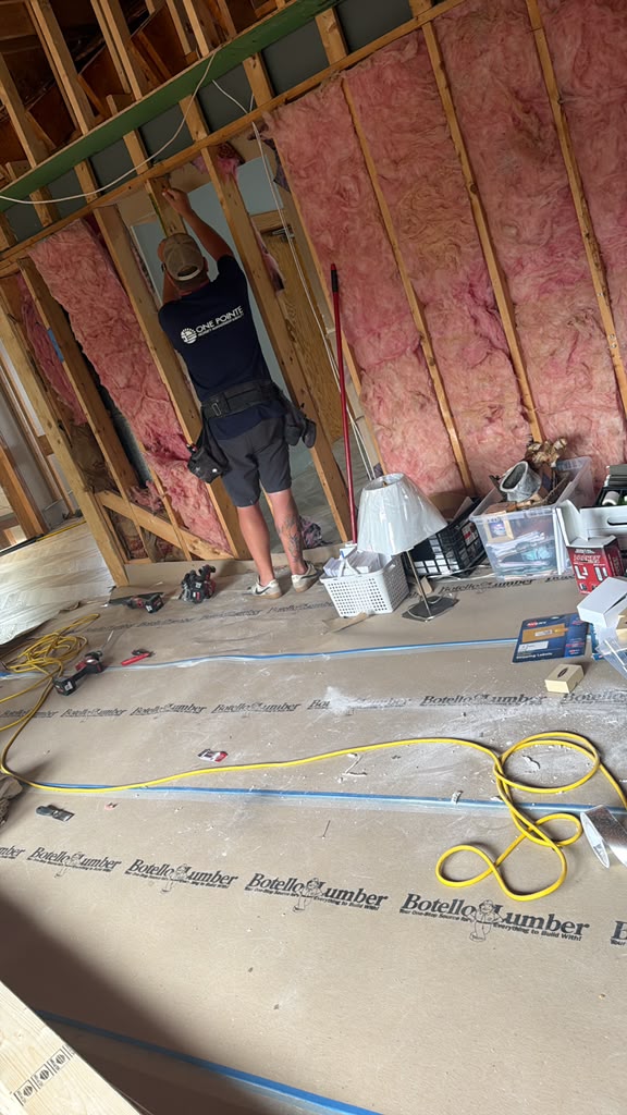 Carpenter working on interior wall framing with insulation in place