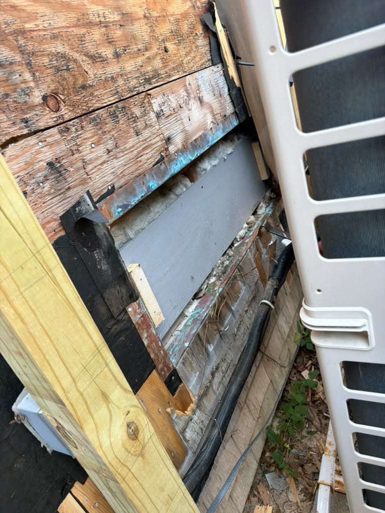 Exterior wall opened up showing removed siding, old sheathing and insulation before repair